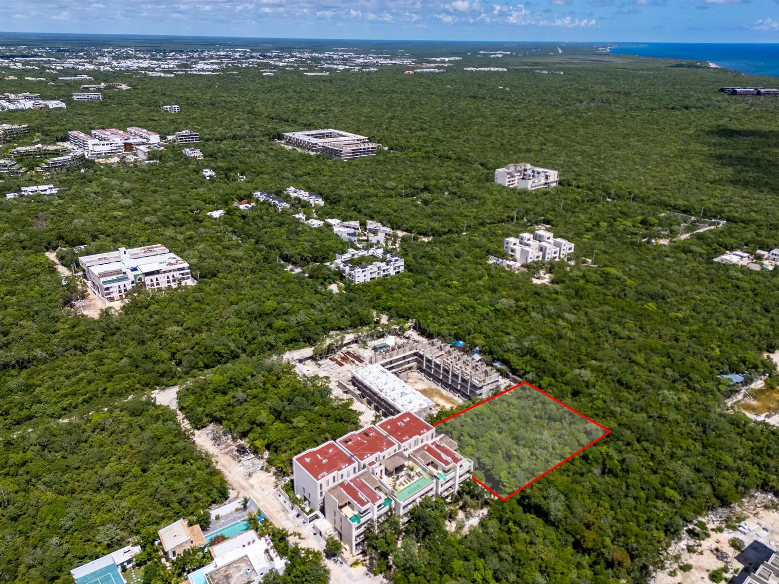 Wide drone view of La Veleta's jungle and buildings, Lot 644 outlined in red, the Caribbean on the horizon